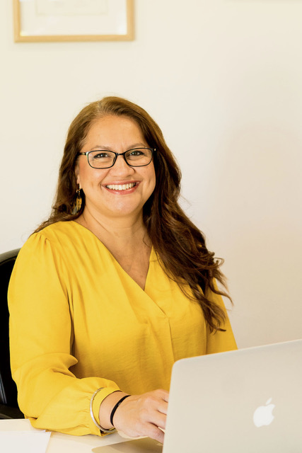 Sim Dhaliwal, speech pathologist and educator, smiling at her desk